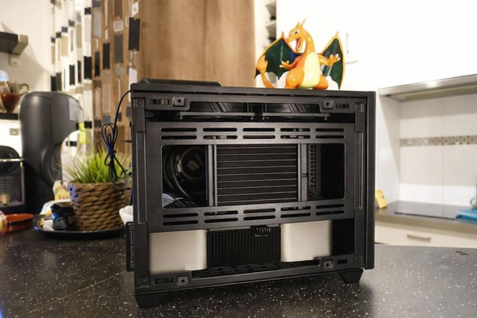 Öppet ITX-datorchassi på bänkskiva, med figur ovanpå höljet.