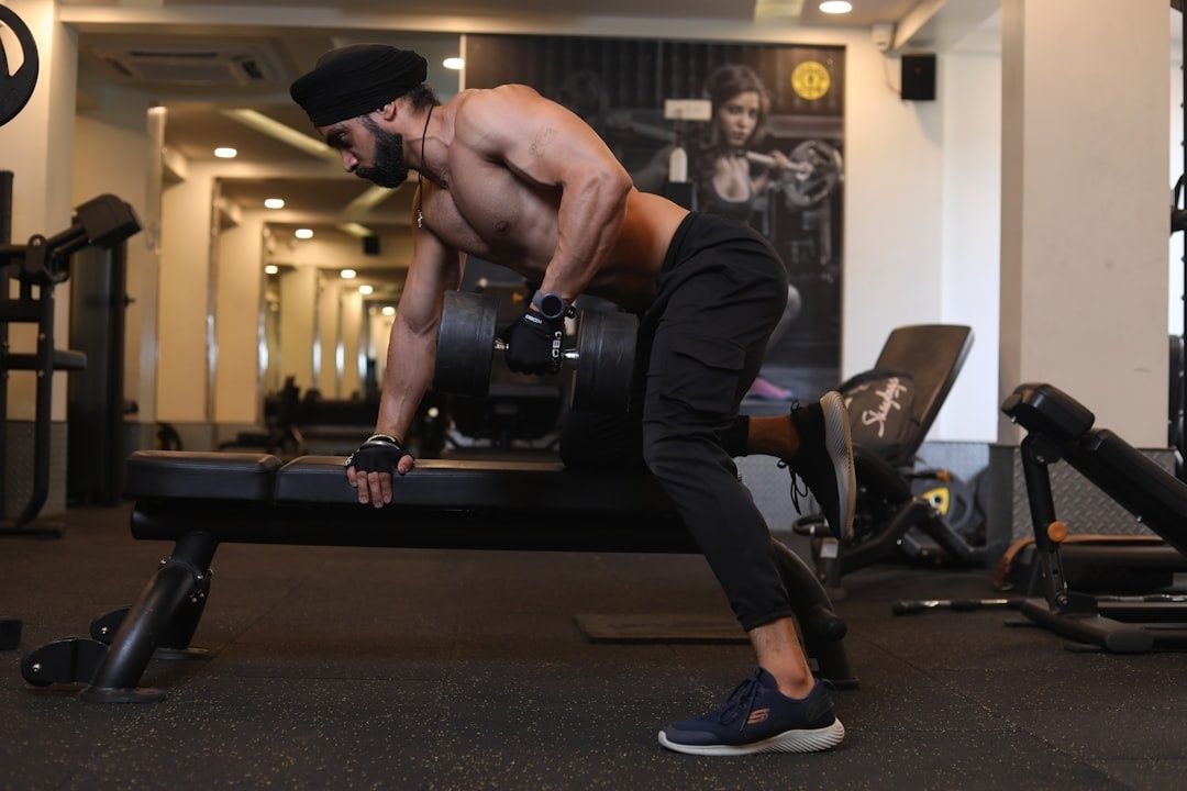 Barbröstad man tränar med hantel och bänk på gym